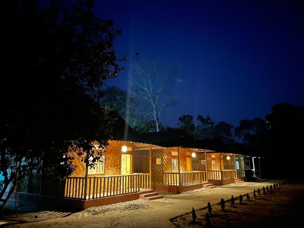 A wooden cabin with a porch, illuminated windows, and a clear night sky.