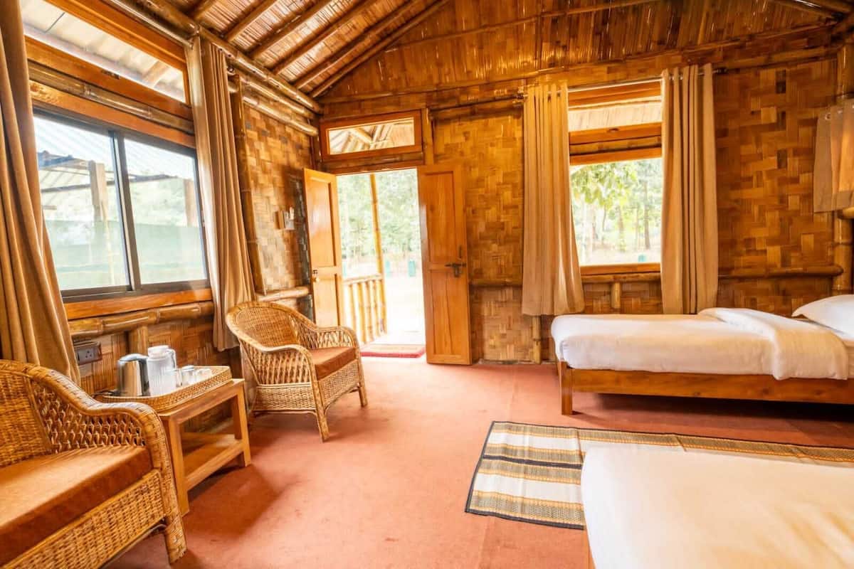 Een kamer met houten vloer, een bed, twee stoelen, een tafeltje en een raam.