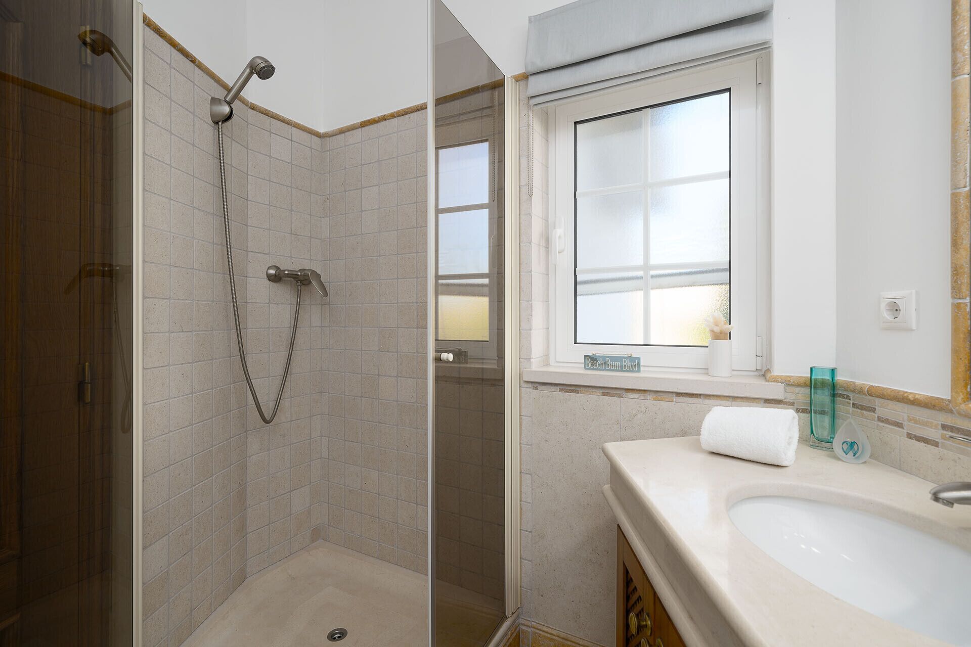 Ein Badezimmer mit Dusche, Waschbecken und Fenster.