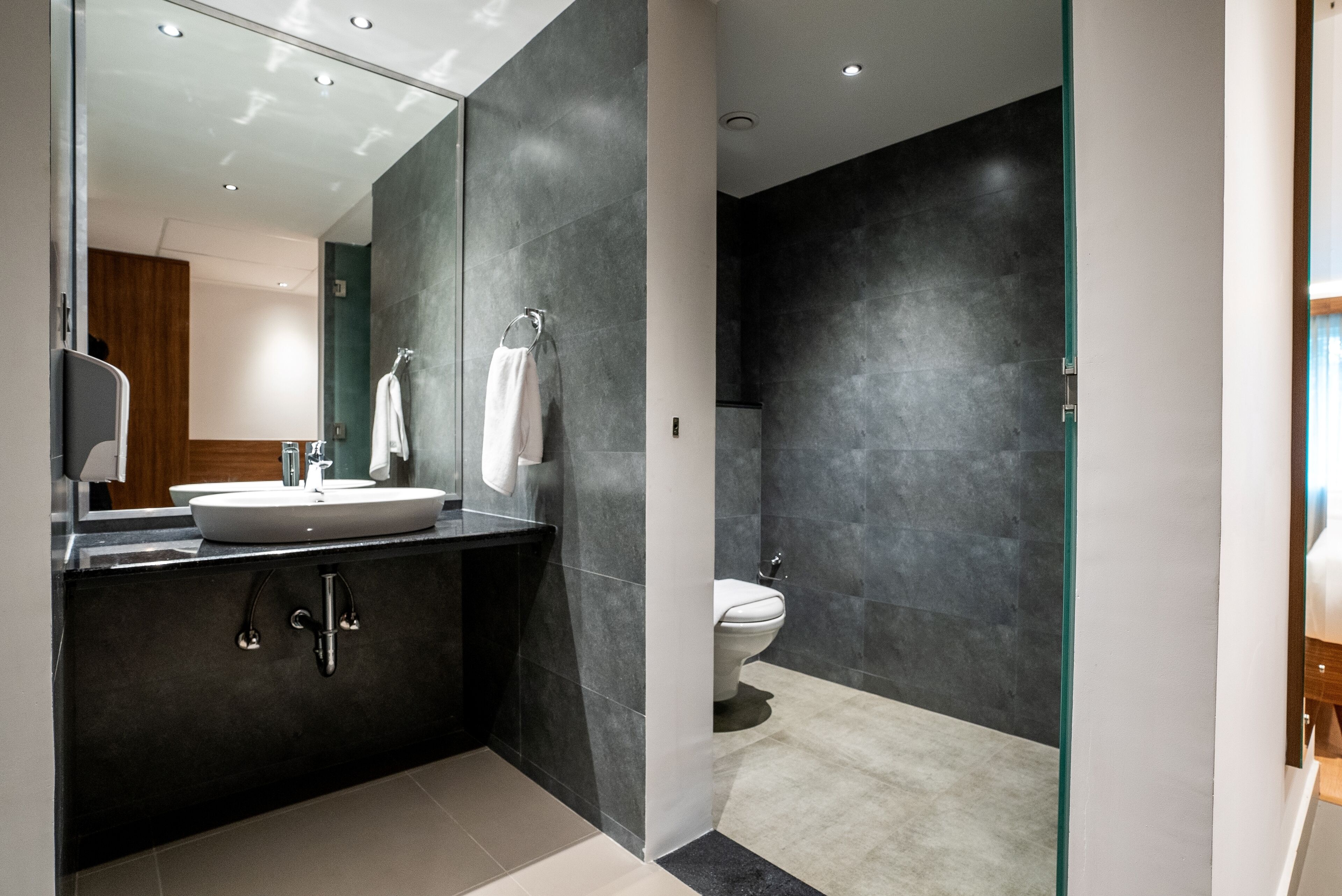 A modern bathroom with a large mirror, a sink, and a toilet.