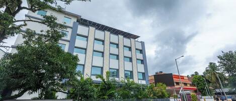 Un edificio de varios pisos con un diseño arquitectónico moderno, que presenta una serie de ventanas y un panel solar en el techo.