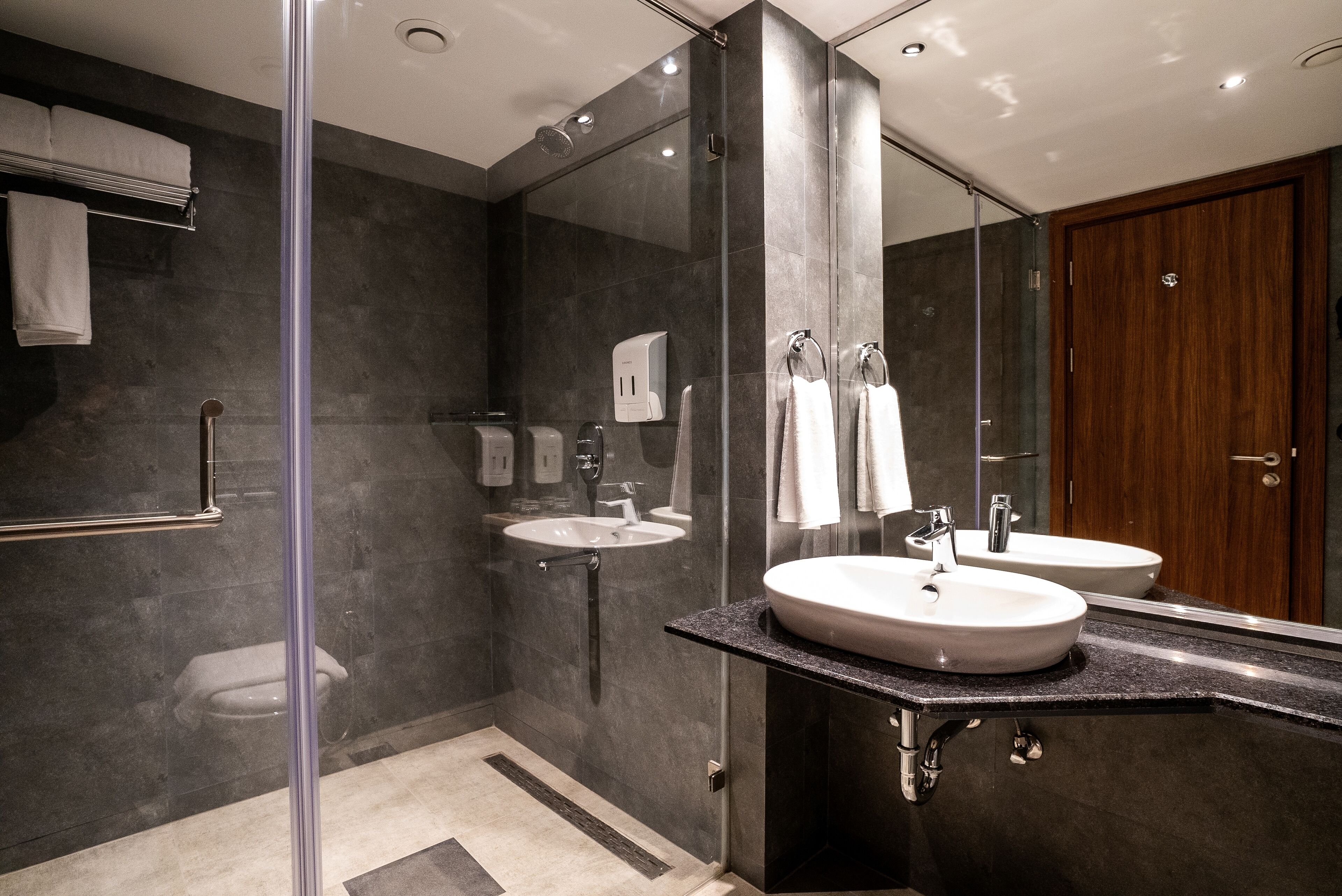 A modern bathroom with a glass shower enclosure, two sinks, and a large mirror.