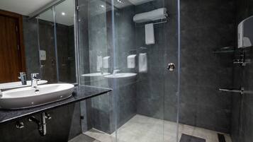 Un bagno moderno con doccia vetrata, due lavabi e un porta asciugamani.
