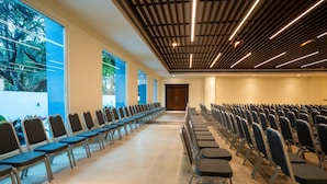 Un salón de conferencias con filas de sillas y un ventanal grande.