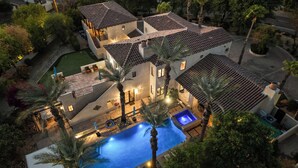 Une grande maison avec une piscine, plusieurs terrasses et un jardin bien entretenu.