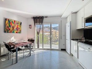 A dining area with a table, chairs, and a view through a glass door to the outside.