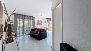 Una sala moderna con un sofá negro, una mesa de centro y un mueble para televisión.