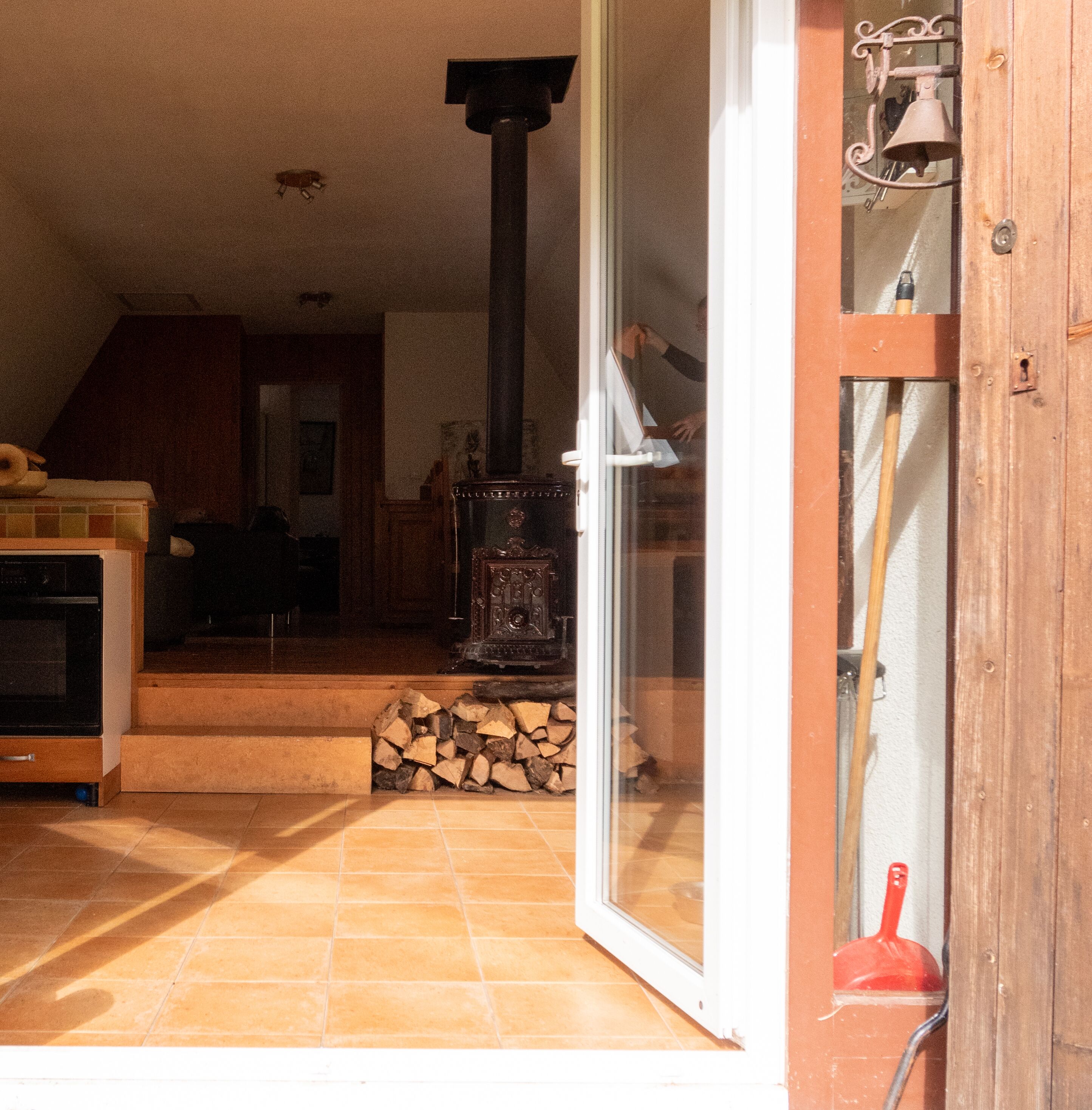 Ein gemütliches Wohnzimmer mit Kamin, einer Holztreppe und einer Glastür, die nach draußen führt.