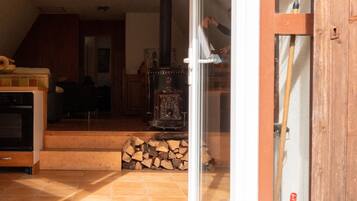 Ein gemütliches Wohnzimmer mit Kamin, einer Holztreppe und einer Glastür, die nach draußen führt.
