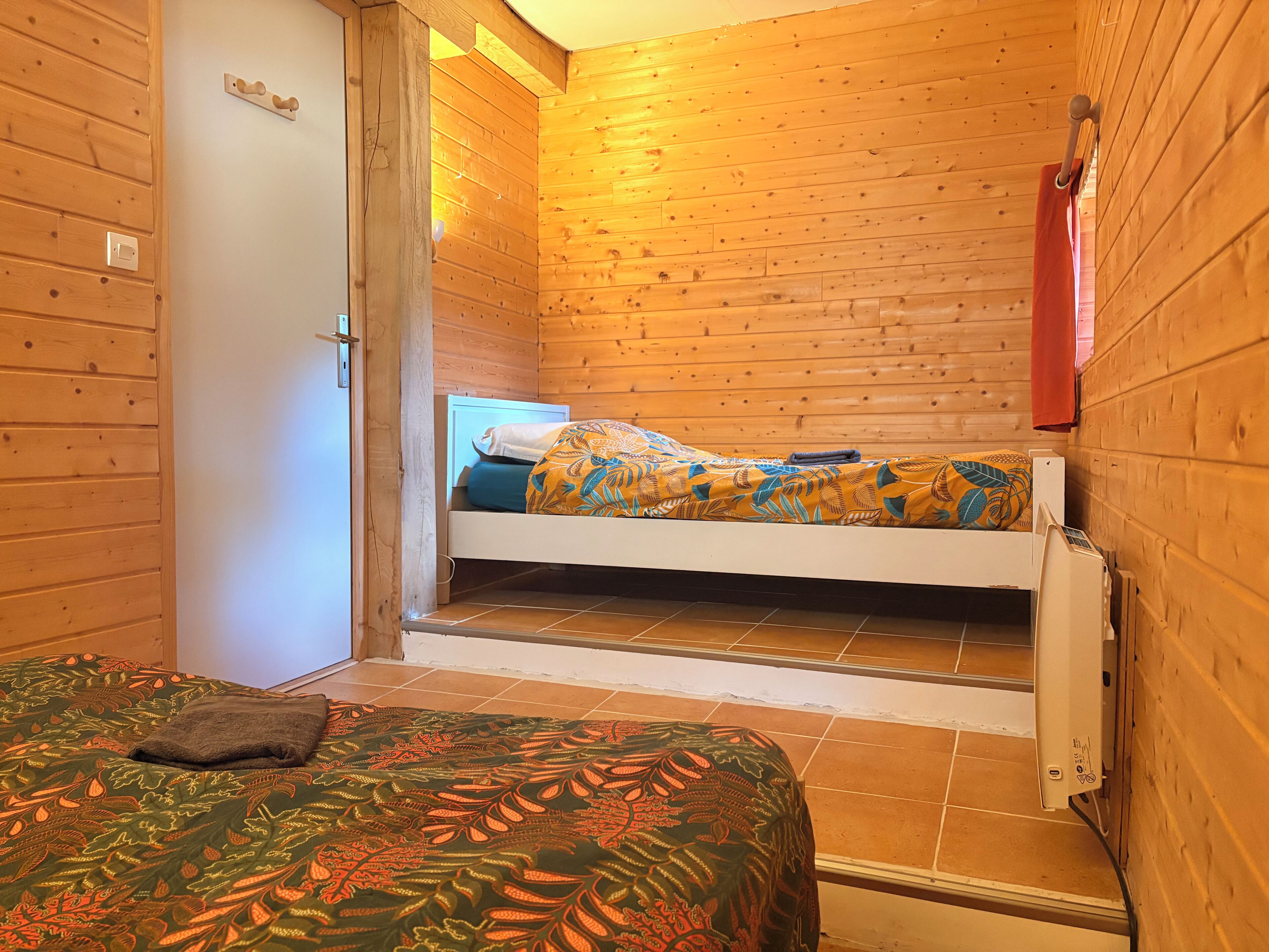 Een houten kamer met een bed, een bank en een deur.