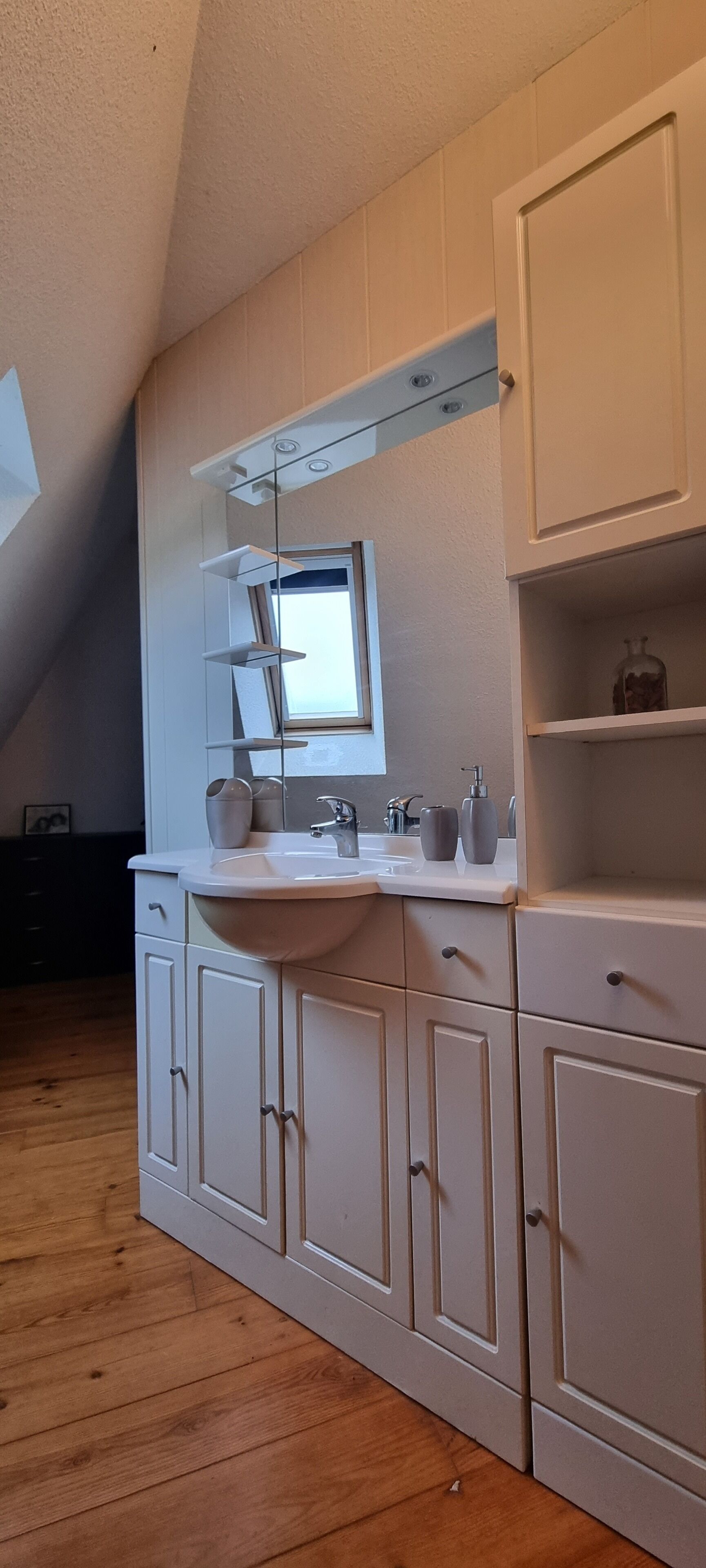 Een keuken met witte kastjes, een wit aanrecht en een raam boven de gootsteen.