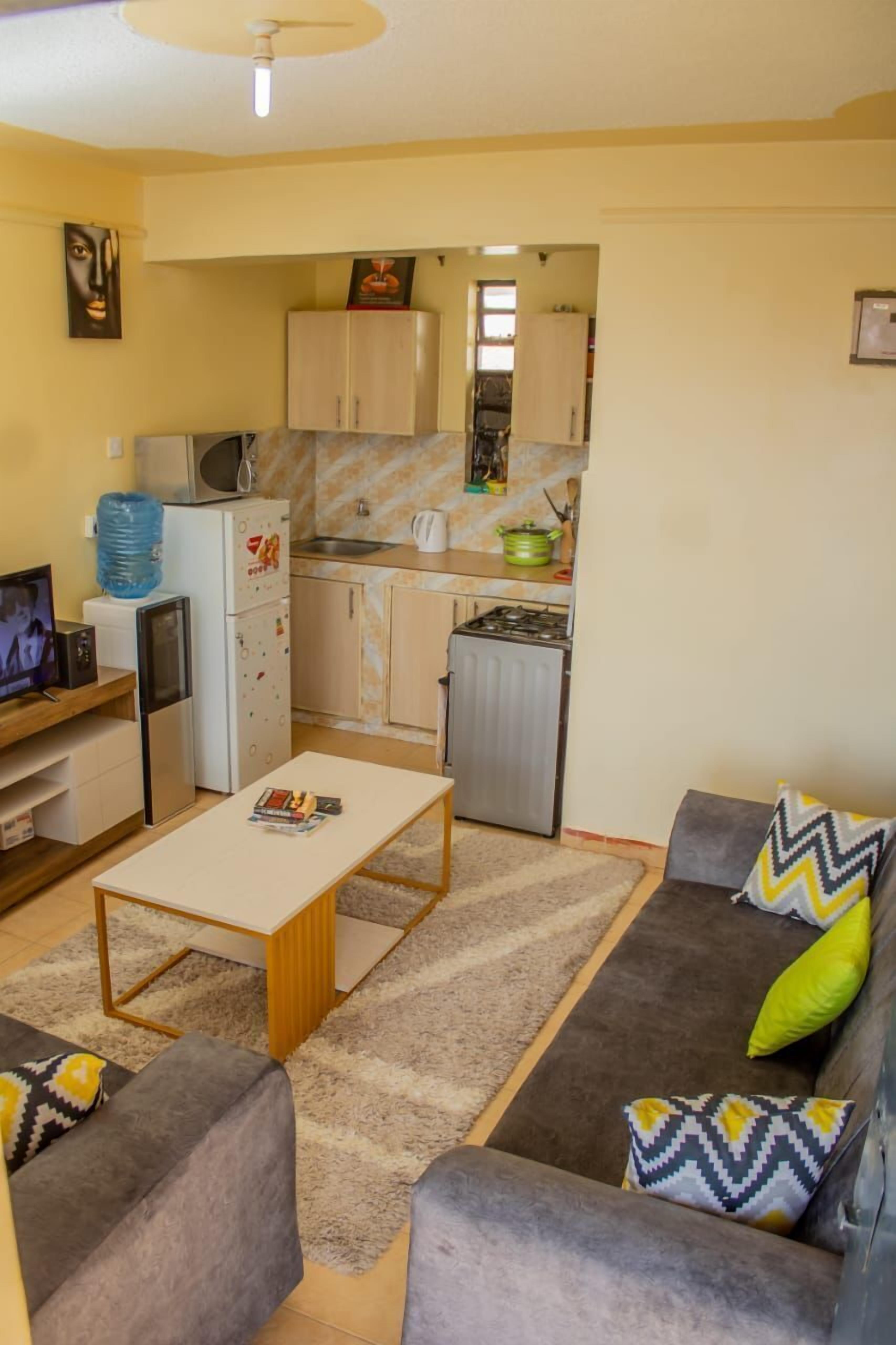 Een knus woongedeelte met een kitchenette, een zithoek, een salontafel en een televisie.