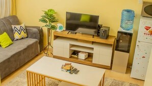 A living room with a sofa, coffee table, TV, and artwork on the wall.