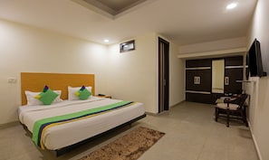 A bedroom with a bed, a bedside table, a telephone, a mirror, a wardrobe, and a chair. - Treebo Royal Palace, New Delhi (New Delhi)