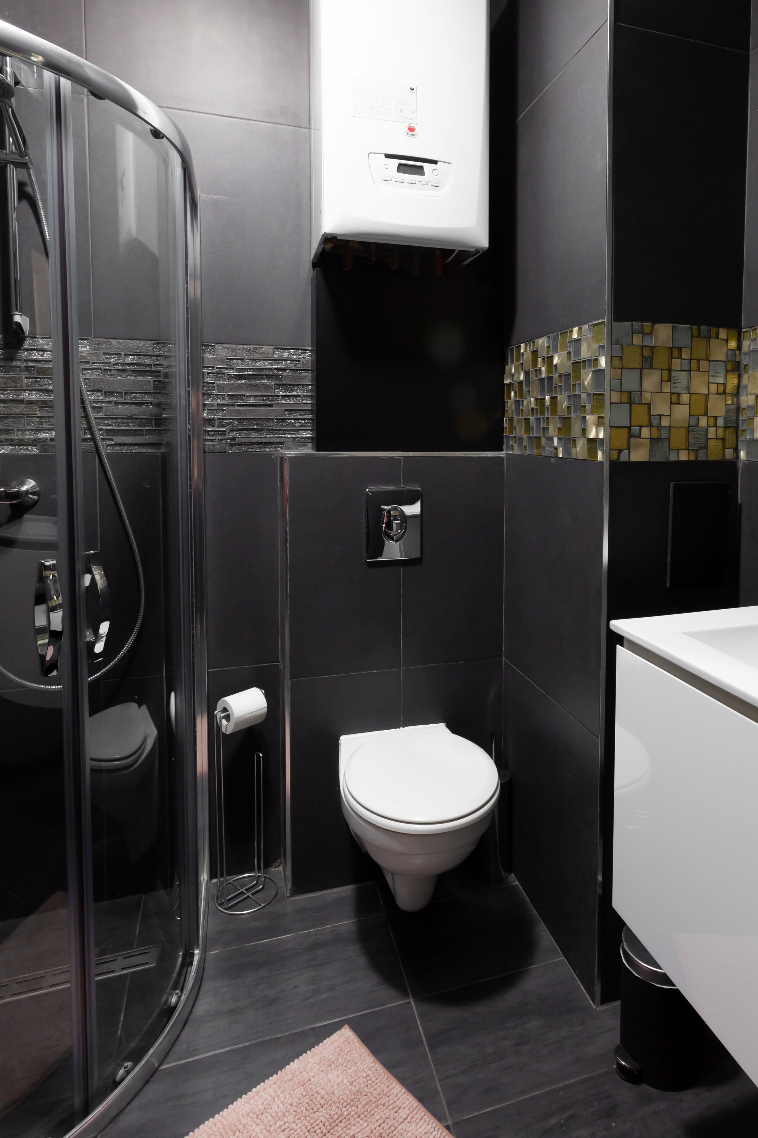 A modern bathroom with a glass-enclosed shower, a toilet, and a white sink.