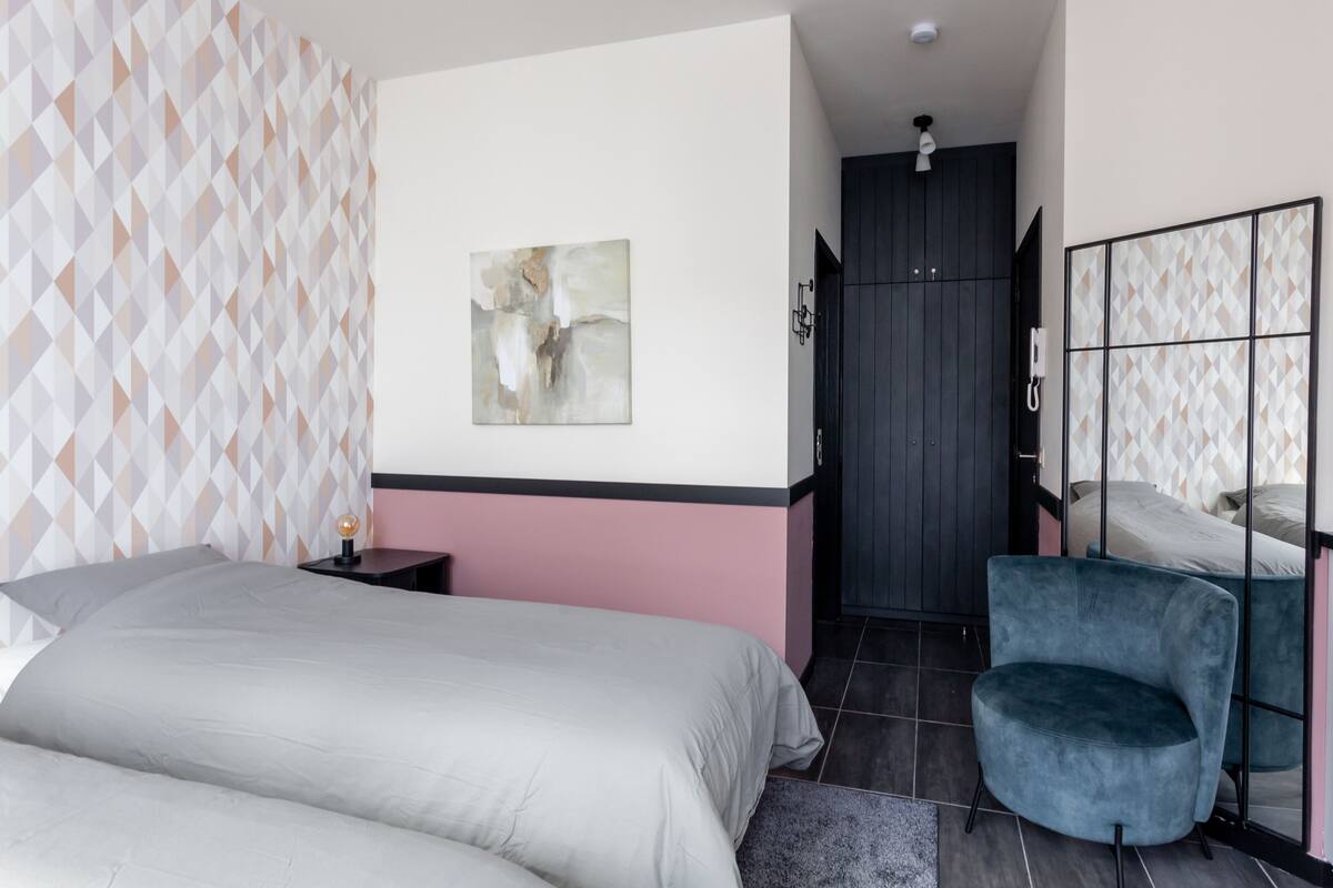A bedroom with a bed, a chair, a wardrobe, and a painting on the wall.