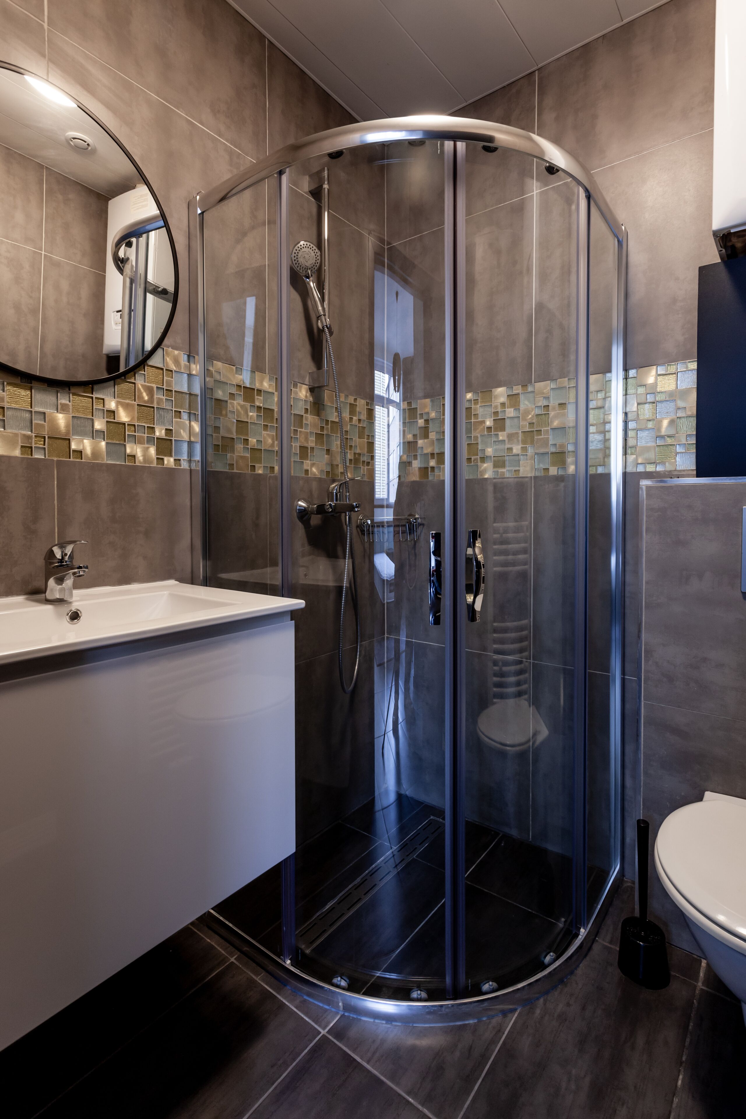 Ein modernes Badezimmer mit einer Duschkabine, einem weißen Waschbecken und einer Toilette.