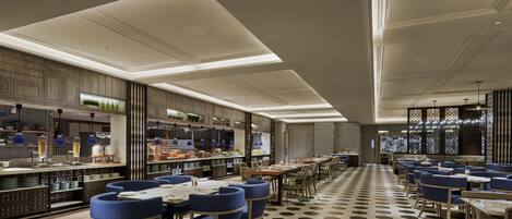 A modern restaurant with a long counter, blue upholstered chairs, and a patterned floor.