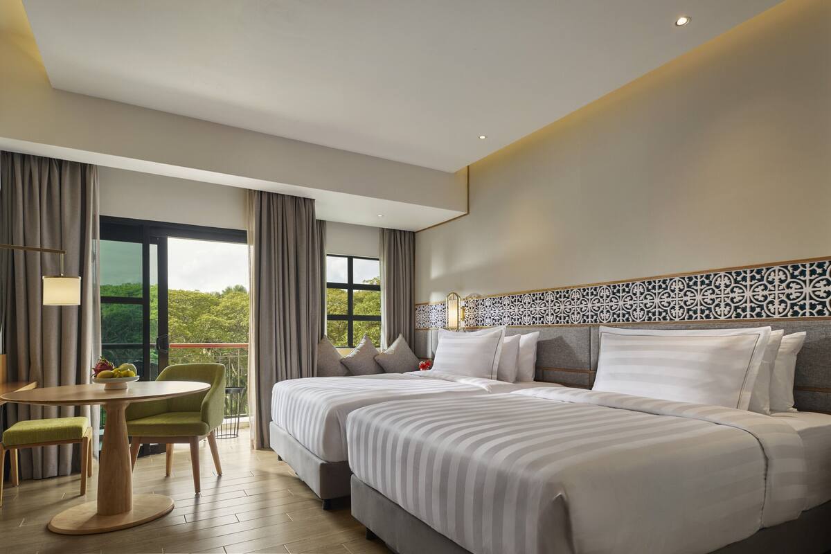Een hotelkamer met een groot bed, een bureau met stoel, en een balkon met gordijnen.