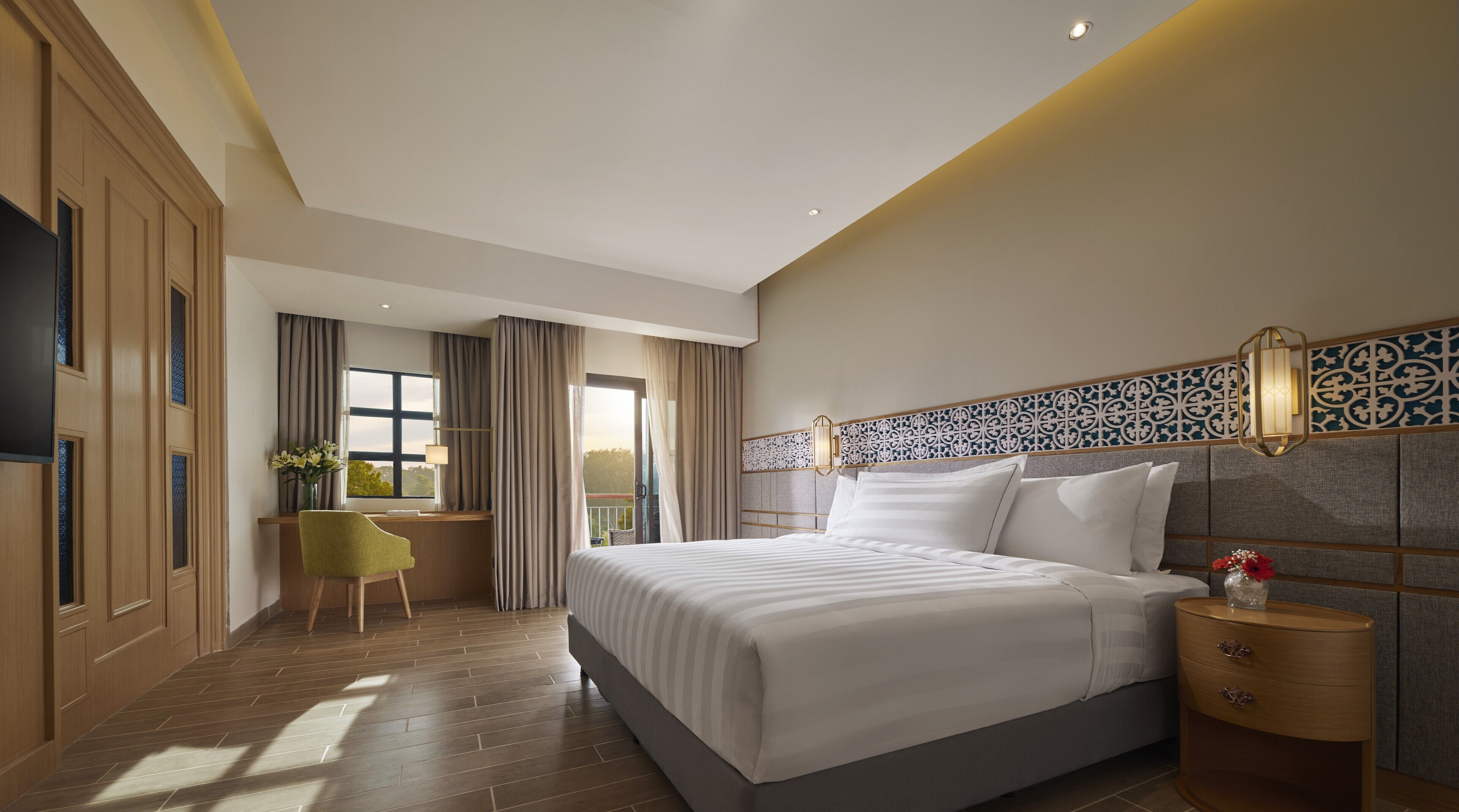 A modern hotel room with a large bed, a desk, and a view of the outdoors.