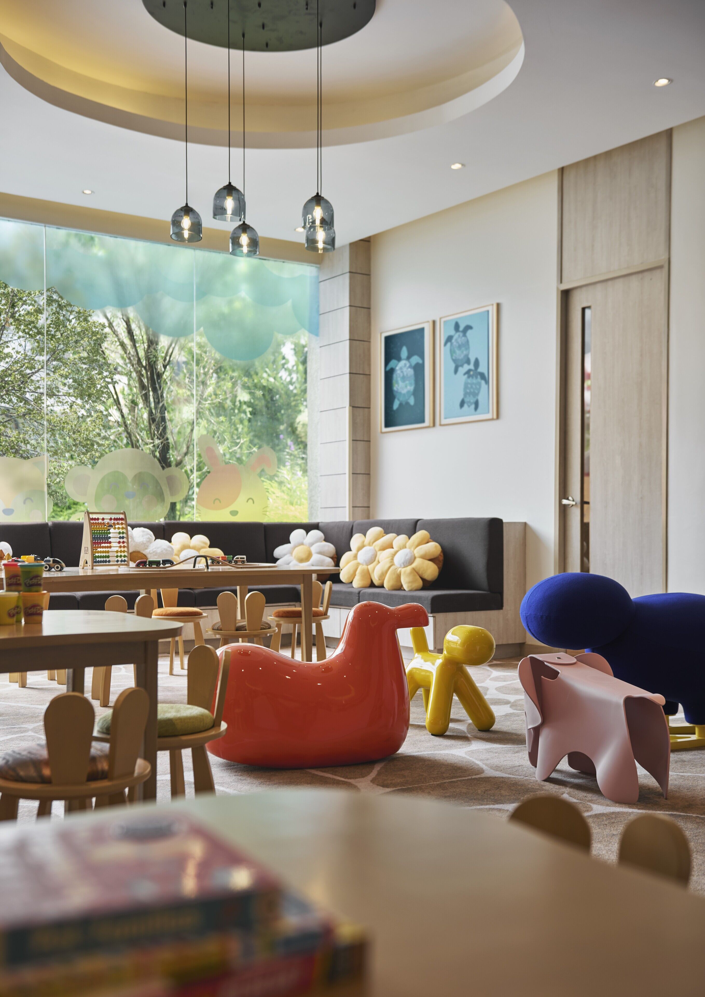 Ein modernes Wohnzimmer mit großem Fenster, einer Couch, einem Fernseher und bunten Sesseln.