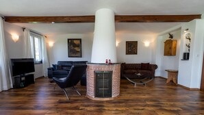 Ein Wohnzimmer mit Kamin, Holzböden, einem Fernseher und zwei Sofas.