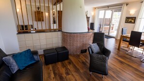 Ein modernes Wohnzimmer mit Kamin, Ledersofas und einem Essbereich.