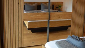 A modern bedroom with a wooden bed frame, a bedside table, and a nightstand. - Chalet 125qm für Max. 6 Personen, 3 Sep. Schlafzimmer (Reit im Winkl)