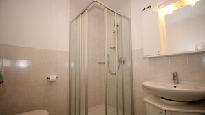 Een badkamer met een douche met glazen wand, een toilet en een wastafel met spiegel erboven.