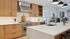 A modern kitchen with wooden cabinets, a central island, and a built-in stove.
