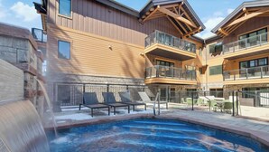 A hotel with a pool area, outdoor seating, and a waterfall feature.
