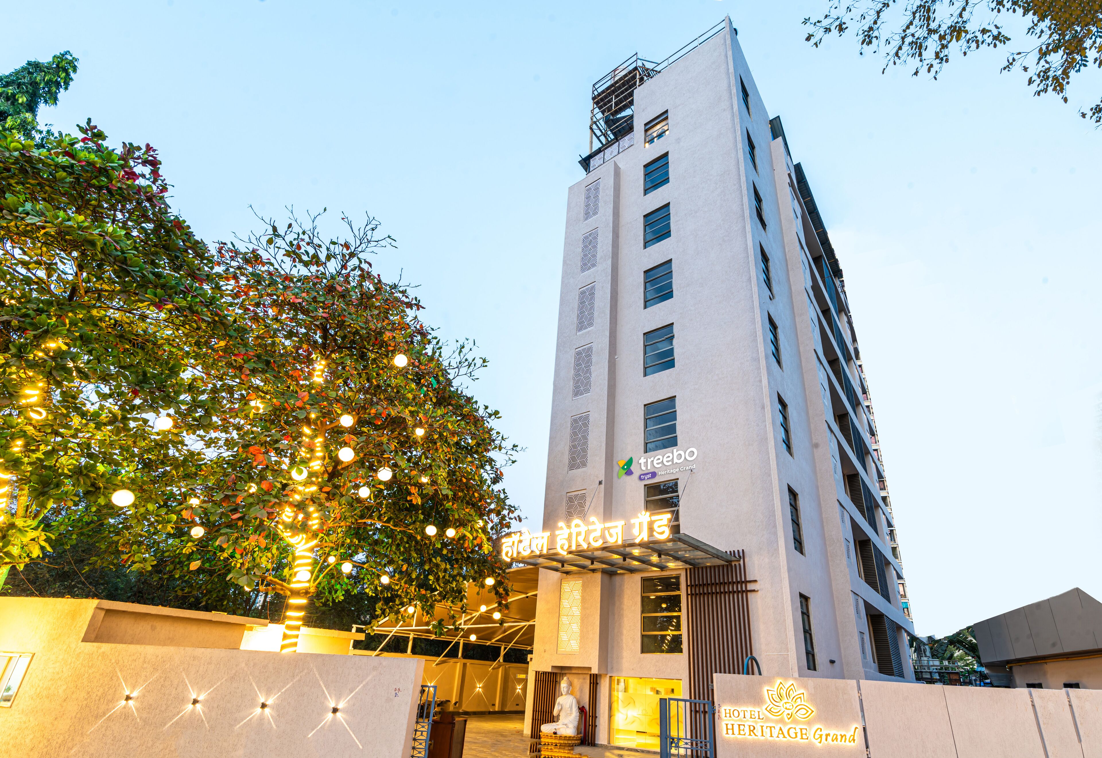 A hotel with a modern facade, a prominent entrance with a sign, and a statue in front.