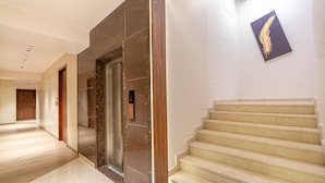 A modern hotel lobby with a marble staircase, a reception area, and a wall-mounted artwork. - Treebo Premium Heritage Grand, Thane (Thane)