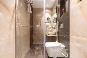 A modern bathroom with a glass-enclosed shower, a white toilet, a sink, and a vanity mirror.
