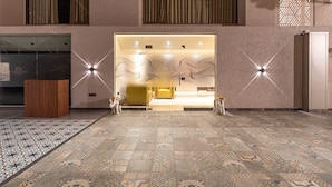 A hotel lobby with a patterned floor, a reception desk, and a large illuminated entrance. - Treebo Premium Heritage Grand, Thane (Thane)
