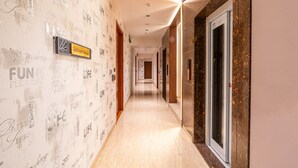 A hotel hallway with a patterned wall, a sign with numbers, and a door. - Treebo Premium Heritage Grand, Thane (Thane)