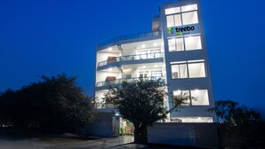 A multi-story building with a 'treebo' sign, featuring balconies and a gated entrance. - Treebo Fortune Home Expressway (Noida)