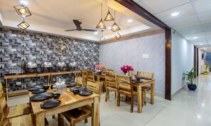 A dining area with a wooden table set for six, surrounded by chairs. - Treebo Fortune Home Expressway (Noida)