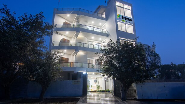 A multi-story hotel with a modern design, featuring balconies and a well-lit entrance. - Treebo Fortune Home Expressway (Noida)
