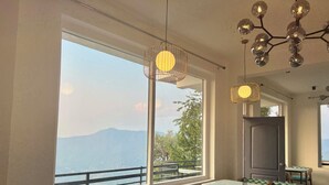 Een restaurant met grote ramen met uitzicht op bergen en een meer. Tafels en stoelen staan er klaar voor dineren.