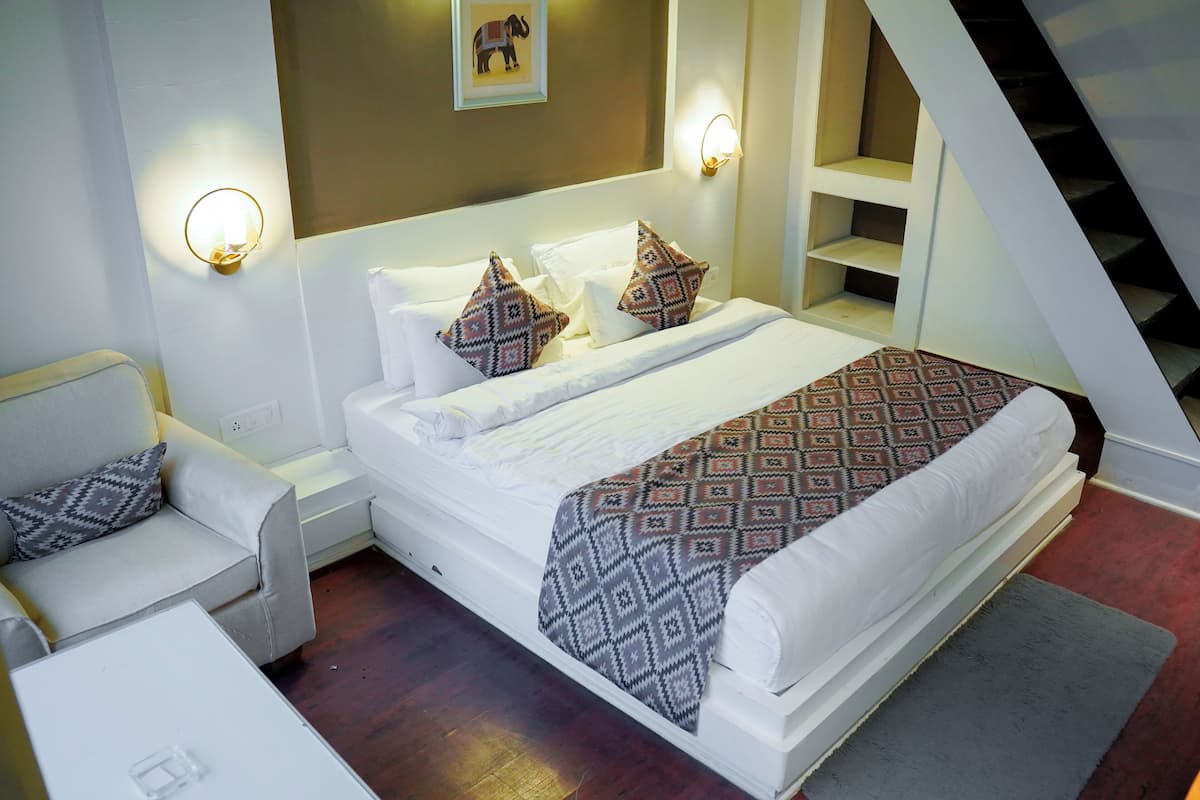 Ein Schlafzimmer mit einem Bett, einem Nachttisch, einer Couch und einer Treppe.