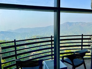 Un balcon avec une table et des chaises, offrant une vue sur un paysage montagneux.