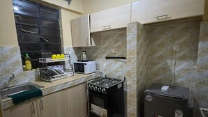 Une cuisine de taille réduite équipée d’une cuisinière à gaz, d’un four à micro-ondes et d’un réfrigérateur.