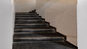 A staircase with black steps and beige walls. - Itsy Hotels Signature, Nehru Nagar (Ahmedabad)
