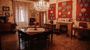 A dining room with a wooden table, chairs, a chandelier, and a fireplace. - Pergi Palace (Tolfa)