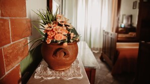 A terracotta pot with flowers on a table in a hallway. - Pergi Palace (Tolfa)
