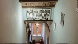 A staircase leading to a landing with a wooden ceiling and a wall-mounted light fixture. - Pergi Palace (Tolfa)