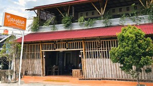 A two-story building with a red roof and a sign that reads "CAMA NA". - Vamana Bangsal (Pemenang)