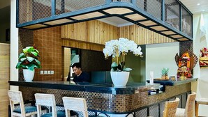 A reception area with a counter, chairs, and decorative plants. - Vamana Bangsal (Pemenang)