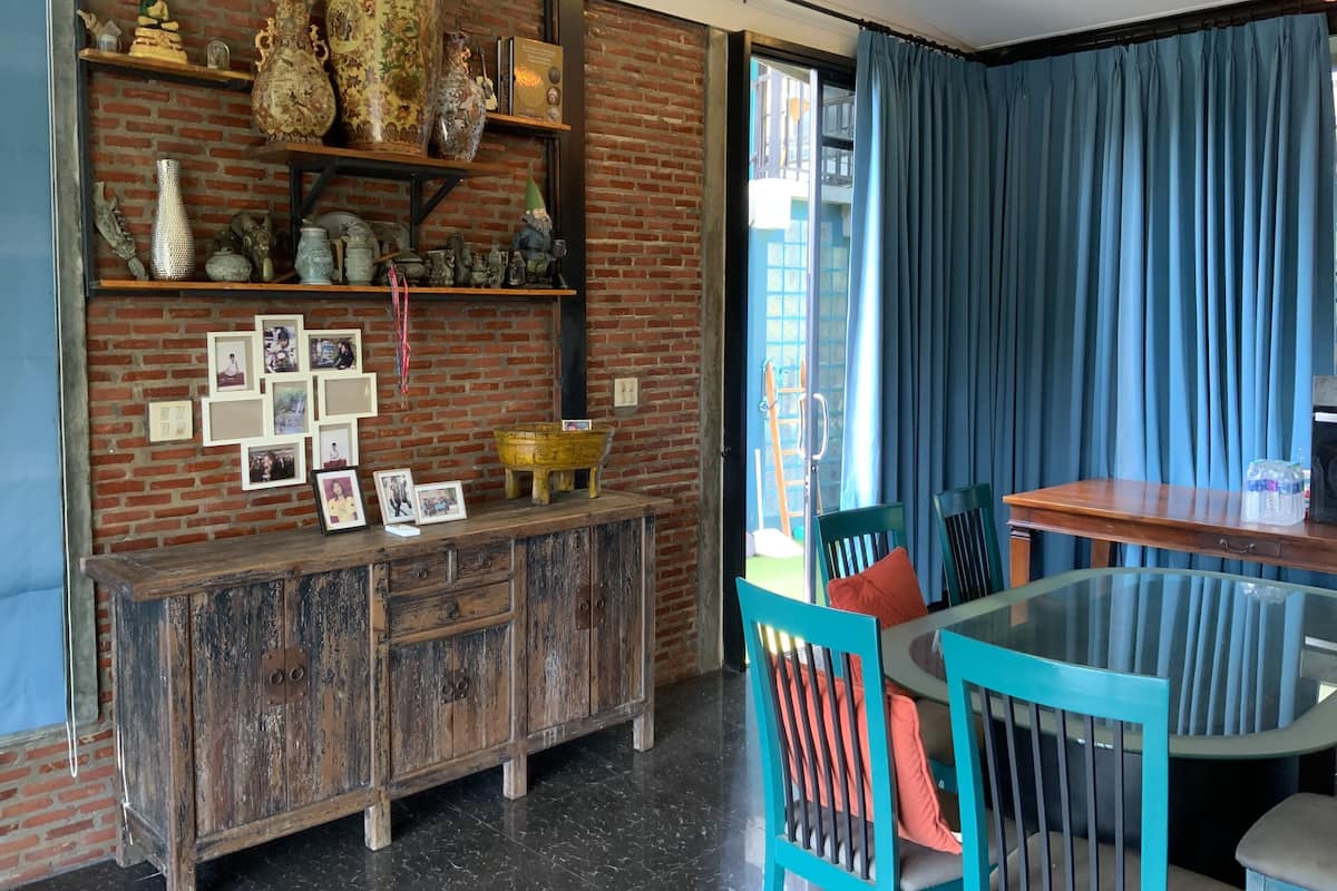 A room with a brick wall, wooden furniture, and a glass table.